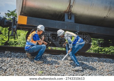 Diverse engineers inspecting train wheels and tanker undercarriage for safety maintenance, African and Asian railway technicians performing a technical check on an oil tanker wagon