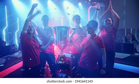Diverse Esport Team Winner of the Video Games Tournament Celebrates Victory Cheering and Holding Trophy in Big Championship Arena. Cyber Gaming Event with Gamers and Fans. - Shutterstock ID 1941641143