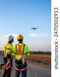 Diverse ethnicity male technicians working in the wind turbines field. Innovation engineer men wearing safety gear, controlling flying drone work to develop environmental clean energy at windmill farm