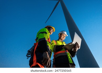 Diverse ethnicity male technicians working in the wind turbines field. Innovation engineer men use laptop computer work to develop environmental renewable clean energy outdoors at windmill power farm. - Powered by Shutterstock