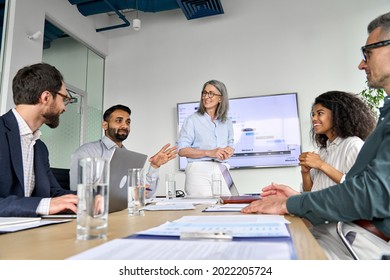 Diverse Executive Team People Discussing Company Strategy At Board Meeting. Multicultural Employees With Senior Leader Listening Indian Manager Brainstorming Working Sitting At Table In Office.