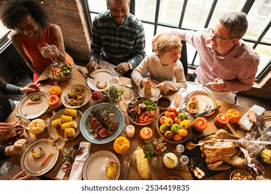 Diverse family enjoying a Thanksgiving festive meal. Laughter and food shared on a table. Thanksgiving celebration with family, delicious and joyful. Diverse family enjoy Thanksgiving meal together - Powered by Shutterstock