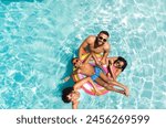 Diverse family enjoys a sunny day in the pool. Smiles radiate as they share a fun and relaxing moment together outdoors.