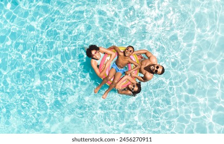 Diverse family enjoys a sunny day at the pool, with copy space. They're relaxing on floaties, capturing the essence of summer fun. - Powered by Shutterstock