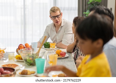 Diverse Family Meeting And Having Dinner Together Sitting At The Table At Home. Caucasian Couple Visiting Relatives. People Enjoy Talking While Eating Food.