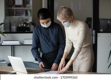 Diverse Female Colleagues Wearing Medical Face Masks Work Together In Office On Quarantine, Woman Coworkers Cooperate At Workplace, Protect From COVID-19 Coronavirus Pandemic, Healthcare Concept