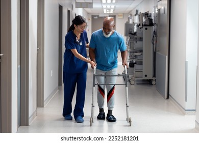 Diverse female doctor helping senior male patient use walking frame in hospital corridor, copy space. Hospital, medical and healthcare services. - Powered by Shutterstock