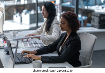 Diverse Female Employees Working At Their Desks In The Office Located In A Skyscraper. Modern Friendly Working Environment