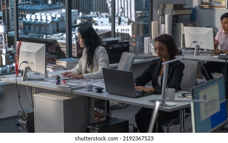 Diverse Female Employees Working At Their Desks In The Office Located In A Skyscraper. Modern Friendly Working Environment