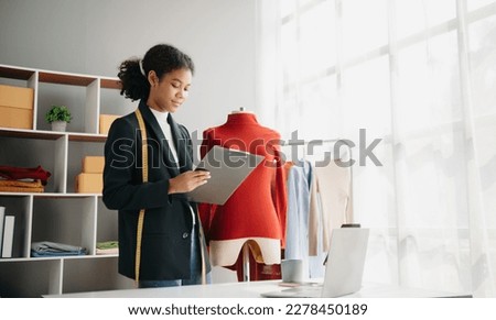 Diverse female fashion designers at work with tailor centimeters on necks and holds tablet and smartphone. independent creative design business. in office