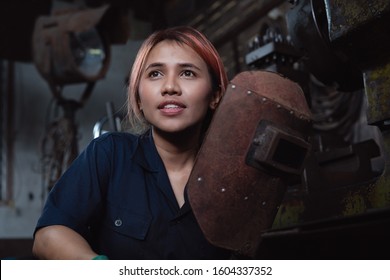 Diverse Female Industrial Engineer Holding Welding Helmet After Work Shift - Young Asian Factory Metal Worker Taking A Break - Hispanic Apprentice Woman Learning New Skills On Internship Training