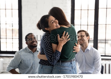 Diverse female patients hug show care support engaged in group counseling session together, happy woman clients embrace recover from addiction, participate in psychological team therapy or training