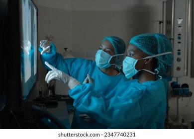 Diverse female surgeons looking at x-ray scans in operating theatre at hospital. Hospital, surgery, hygiene, teamwork, medicine, healthcare and work, unaltered. - Powered by Shutterstock