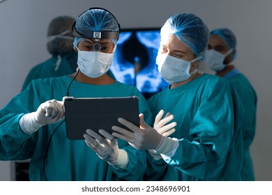 Diverse female surgeons using tablet in operating theatre at hospital. Hospital, surgery, hygiene, teamwork, communication, medicine, healthcare and work, unaltered. - Powered by Shutterstock