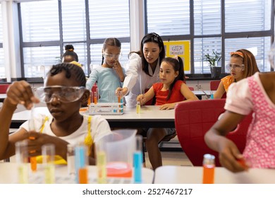 Diverse female teacher and schoolgirls with chemistry items and liquids in elementary school class. School, learning, childhood, science, chemistry and education, unaltered. - Powered by Shutterstock