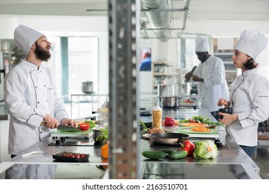 Diverse food industry workers discussing about gourmet dish recipe while cooking in professional kitchen. Chefs talking about what meal to prepare for dinner service at fine dining restaurant. - Powered by Shutterstock