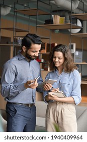 Diverse Friendly Coworkers Talking Using Digital Tablet In Office. Indian Manager Having Discussion With Latin Employee Meeting In Office Lobby Discussing Project, Teaching New Employee Sharing Ideas.