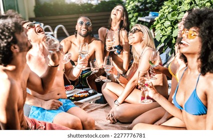 Diverse friends drinking white wine champagne at swimming pool party - Vacation life style concept with happy guys and girls having fun together on summer day at fancy resort - Warm bright filter - Powered by Shutterstock