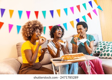 Diverse friends eating a slice of pizza sitting on the sofa celebrating at home - Powered by Shutterstock