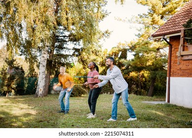 Diverse Friends Playing Badminton Game In The Backyard. Copy Space
