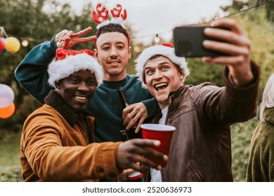 Diverse friends taking a group selfie at a Christmas party. Diverse friends hanging out at a party celebration. Diverse group of fun vibrant people at a Christmas party friendship concept image. - Powered by Shutterstock