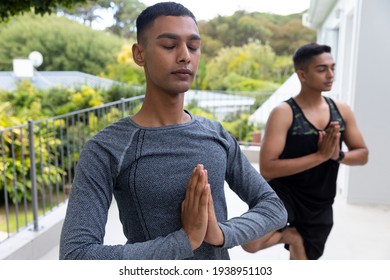 Diverse gay male couple practicing yoga on balcony. staying at home in isolation during quarantine lockdown. - Powered by Shutterstock