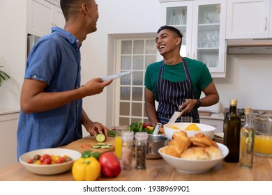 Diverse gay male couple spending time in kitchen cooking together and smiling. staying at home in isolation during quarantine lockdown. - Powered by Shutterstock