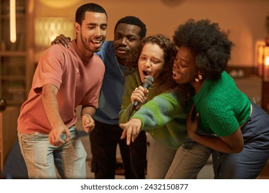 Diverse group of adult friends singing to microphone together and enjoying karaoke together at house party - Powered by Shutterstock