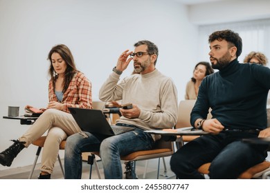 A diverse group of adult learners participate in a class discussion, exhibiting focus, engagement, and collaboration. - Powered by Shutterstock