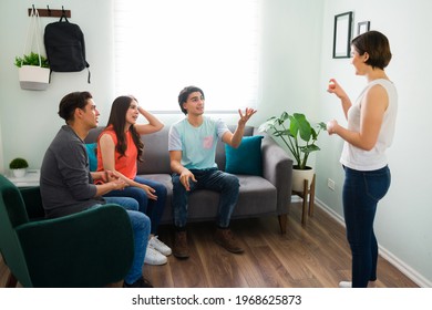 Diverse Group Of Best Friends Playing Charades While Sitting In The Living Room Couch And Trying To Guess The Word To Win The Game