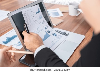 Diverse group of business analyst team analyzing financial data report paper on office table. Chart and graph dashboard by business intelligence analysis for strategic marketing planning Habiliment - Powered by Shutterstock