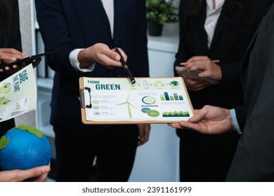 Diverse group of business people discussing for alternative energy utilization for greener sustainable Earth by reducing CO2 emission and carbon credit with renewable clean energy technology. Quaint - Powered by Shutterstock