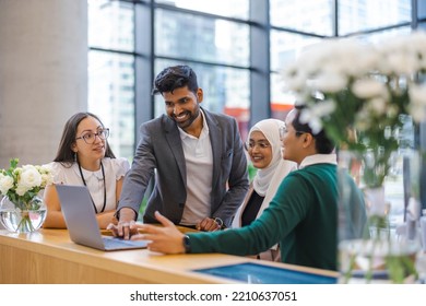 A diverse group of business people gather around a laptop in a modern office - Powered by Shutterstock