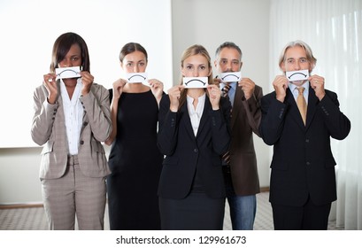 Diverse group of business people holding a card with sad sign by their faces - Powered by Shutterstock