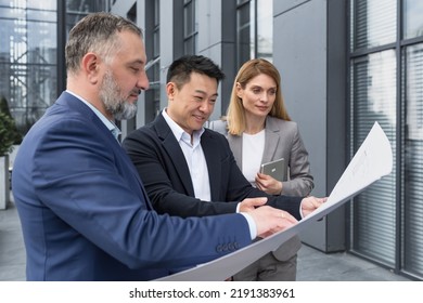 Diverse Group Of Business People Outside Office Building, Discussing And Talking Man And Woman Discussing New Construction Plan, Team Of Business People Holding And Looking At Construction Project