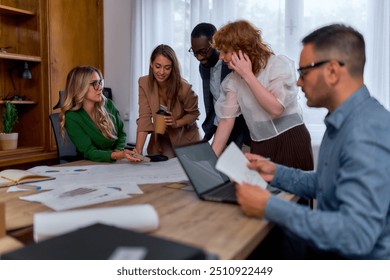 Diverse group of business professionals collaborating on a project in a modern office. They are gathered around a table with documents, charts, and a laptop, discussing ideas and strategies. - Powered by Shutterstock