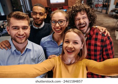 A diverse group of business professionals take a break from their tasks in a modern startup office to capture a creative selfie, showcasing teamwork and a vibrant workplace culture - Powered by Shutterstock