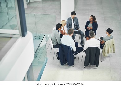 Diverse Group Of Businesspeople, Employees And Colleagues In Seminar Planning, Sitting And Talking Around In A Circle. Coworkers Having A Meeting About A Project At The Office In Corporate Firm.