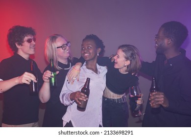 Diverse Group Of Carefree Young People Enjoying Drinks While Partying In Hazy Light