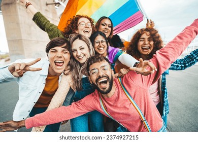 Diverse group of cheerful young people celebrating gay pride day - Lgbt community concept with guys and girls hugging together outdoors 