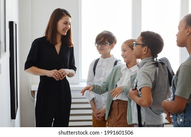 Diverse group of children listening to female tour guide while visiting modern art gallery, copy space - Shutterstock ID 1991601506