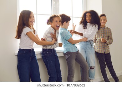 Diverse group of children playing, tickling each other and laughing during break at school or fun party at home. Happy childhood, social interaction with peers, intercultural kids community concepts