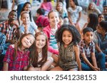 A diverse group of children sitting together, smiling and enjoying. Kids of various ethnicities, including girls and boys, in a cheerful, friendly setting. Cute little diverse kids smiling at camera.