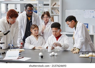 Diverse Group Of Children Wearing Lab Coats In Chemistry Class While Enjoying Science Experiments