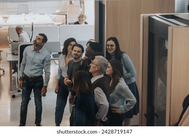 Diverse group of colleagues engaged in a casual office meeting looking upward. - Powered by Shutterstock