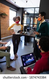 Diverse Group Of Colleagues Wearing Masks Having Disussion In Creative Office. Two Holding Digital Tablets. Hygiene In Workplace During Coronavirus Covid 19 Pandemic.