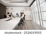 Diverse group of company stakeholders talking at large table in contemporary office workspace. Business colleagues discussing teamwork in stylish meeting room interior. Wide shot with copy space