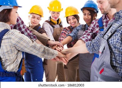 Diverse Group Of Construction Workers Stacking Hands. Isolated On White