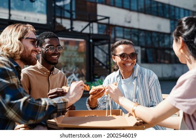 Diverse Group Of Contemporary Young People Enjoying Pizza Outdoors, Scene Lit By Sunlight, Copy Space