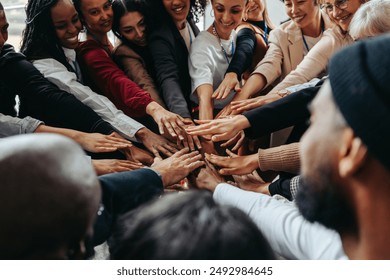 A diverse group of coworkers united in a hands-in huddle, symbolizing teamwork, unity, and collaboration in the workplace. - Powered by Shutterstock